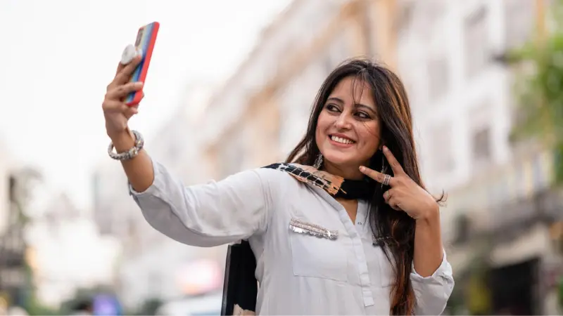 Woman smiling while taking a casual selfie in natural daylight
